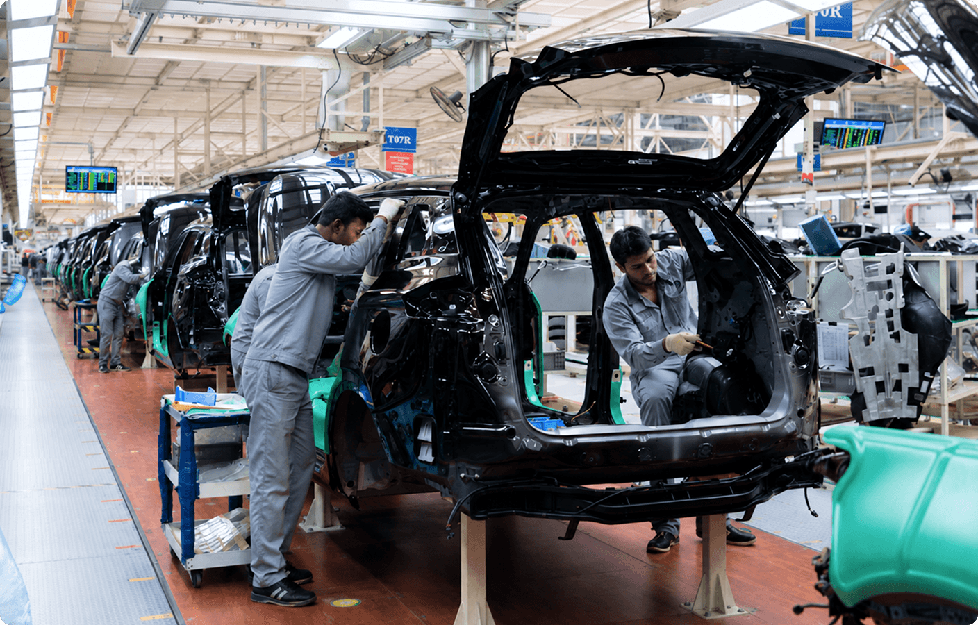 Automobile plant workers assembling a vehicle chassis on the production line