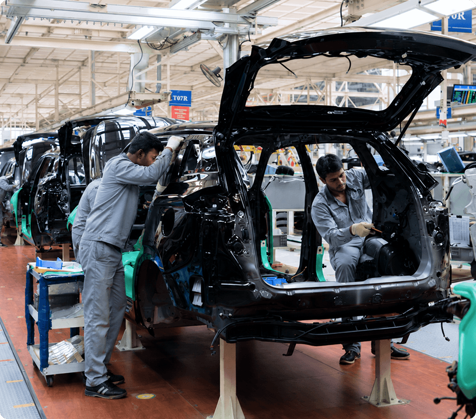 Automobile plant workers assembling a vehicle chassis on the production line