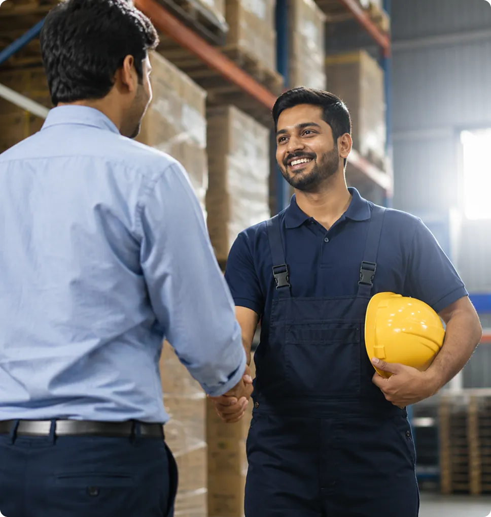 Manager shaking hands with a contract worker holding a hard hat in a warehouse