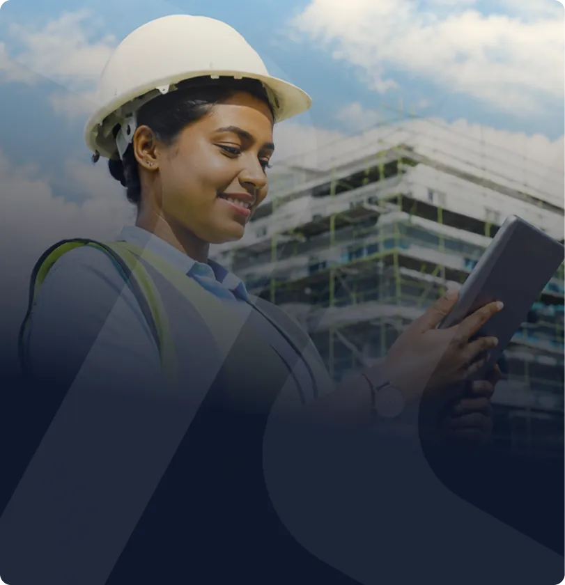 Professional in safety gear using a tablet at a construction site