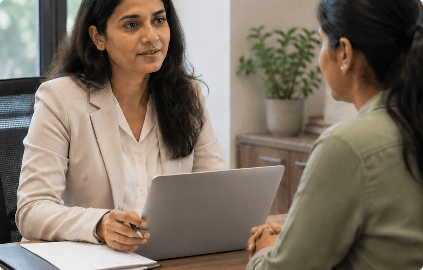 HR professional listening attentively during an employee exit interview at a desk with a laptop and documents