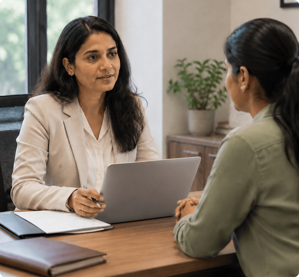HR professional listening attentively during an employee exit interview at a desk with a laptop and documents