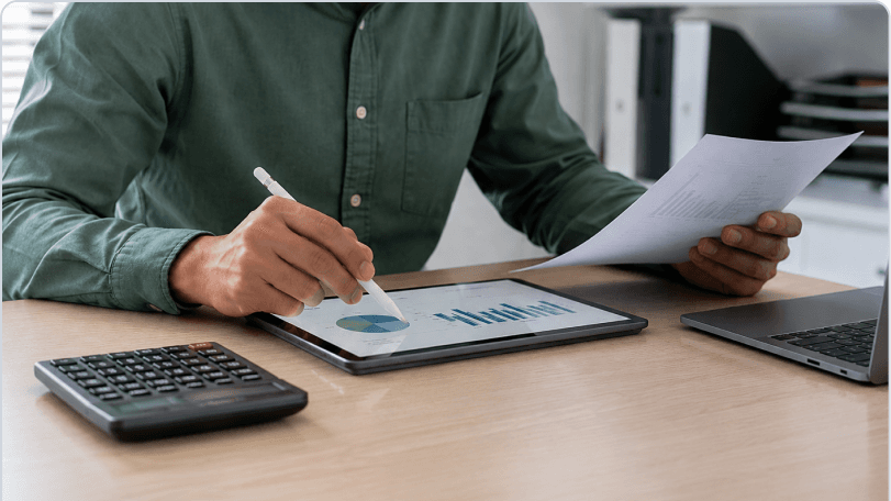 Finance team member reviewing HRMS ROI documents beside a laptop
