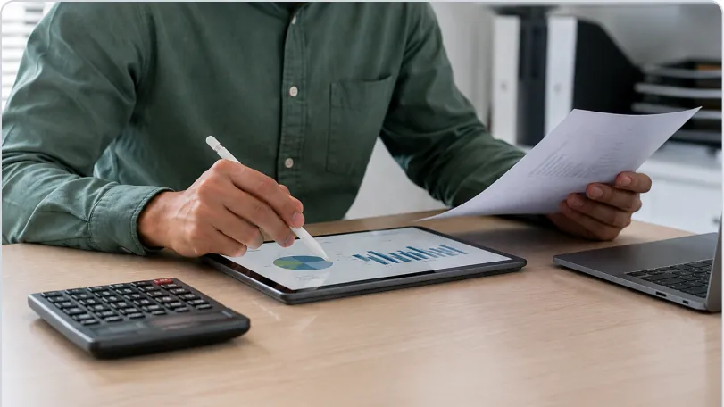 Finance team member reviewing HRMS ROI documents beside a laptop