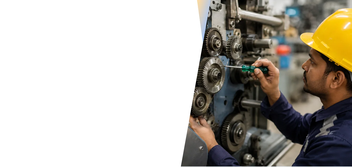 Engineer in a yellow hard hat inspecting industrial machinery with large metal gears in a plant