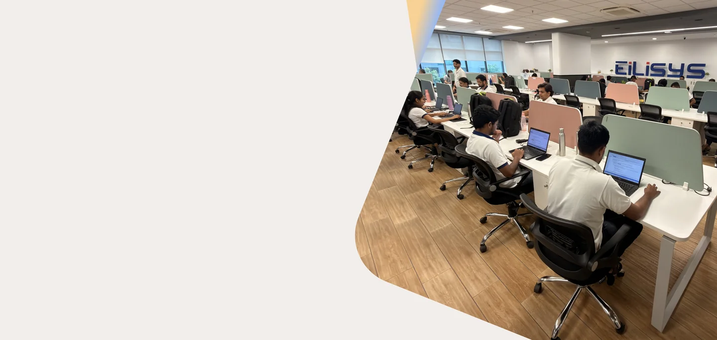 Eilisys team working in a modern open office at long desks with the Eilisys logo on the wall