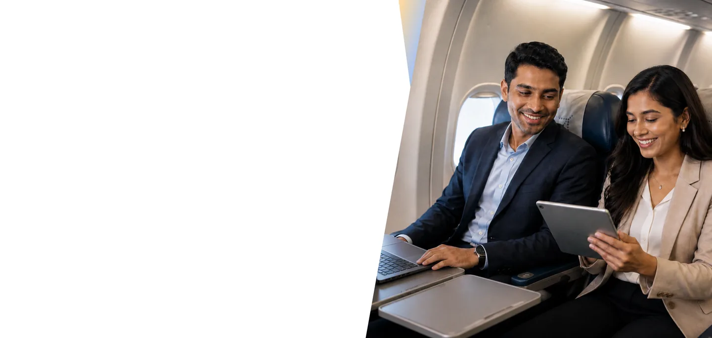 Business professionals collaborating on a laptop and tablet while seated together on an airplane