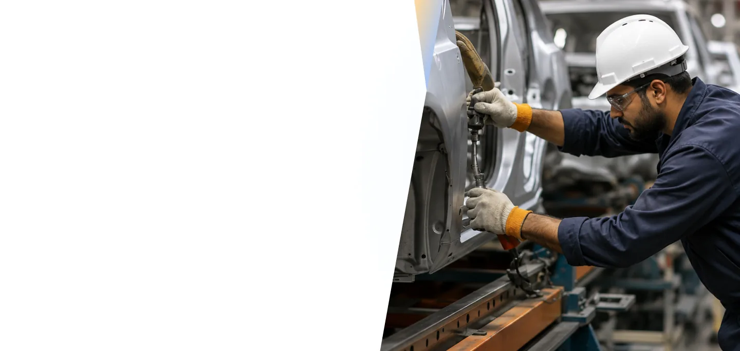 Factory worker in safety gear assembling a vehicle on an enterprise production line